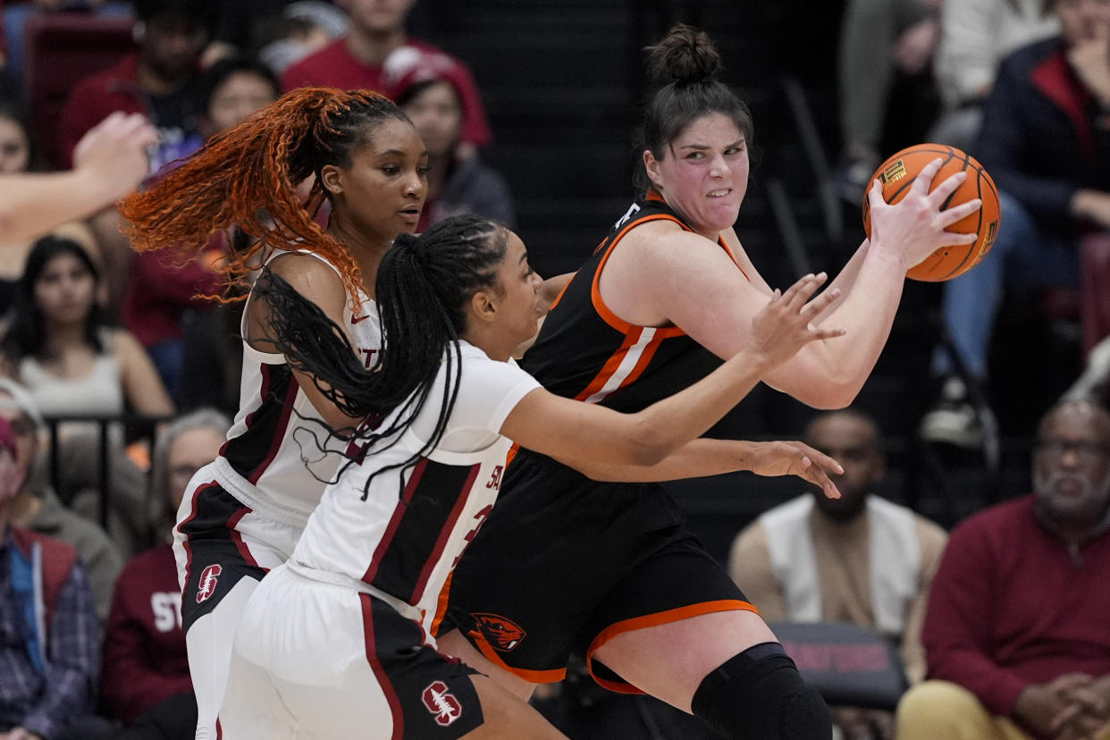 Oregon State forward Raegan Beers, right, looks for an open teammate while defended by Stanford forward Kiki Iriafen, left, and guard Jzaniya Harriel, center, during the second half of an NCAA college basketball game, Sunday, Jan. 21, 2024, in Stanford, Calif. (AP Photo/Godofredo A. Vásquez)