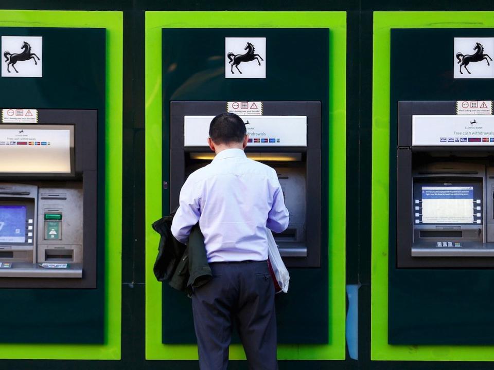 A man uses an ATM outside a branch of Lloyds Bank in London, Britain in this October 28, 2014 file photo.