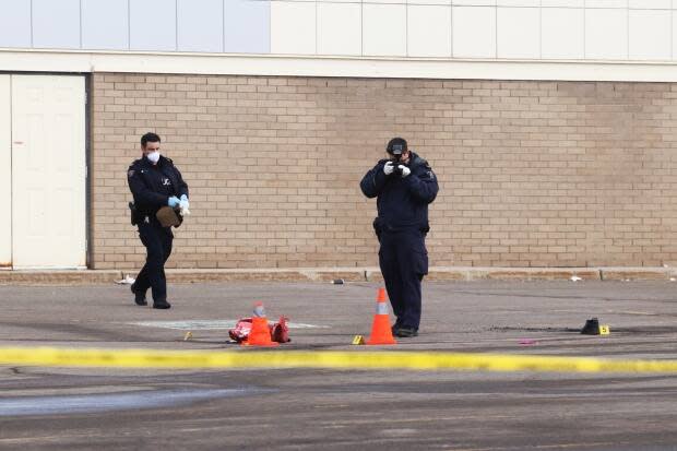 Officers photograph items, including a pair of shoes, in a parking lot near Dooly's on Elmwood Drive in Moncton where Javin Melanson was struck and killed.