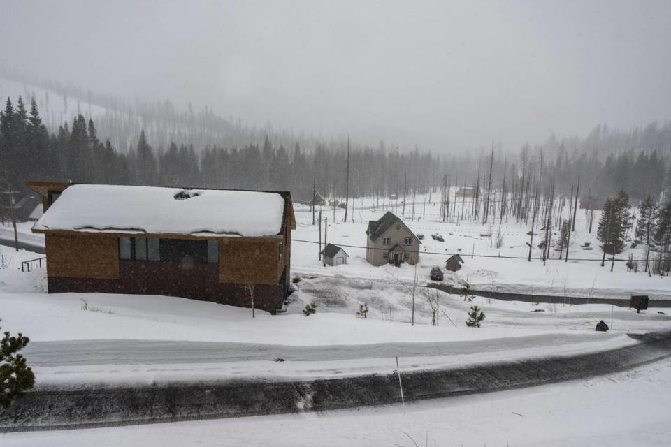 Snow falls on homes on Sierra Pines Road in El Dorado County on Thursday.