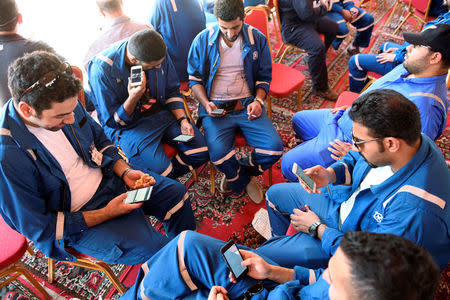 Kuwait Oil and Petrochemical Industries Union workers sit with their cellphones on the first day of an official strike over public sector pay reforms, in Ahmadi, Kuwait April 17, 2016. REUTERS/Stephanie McGehee/File Photo