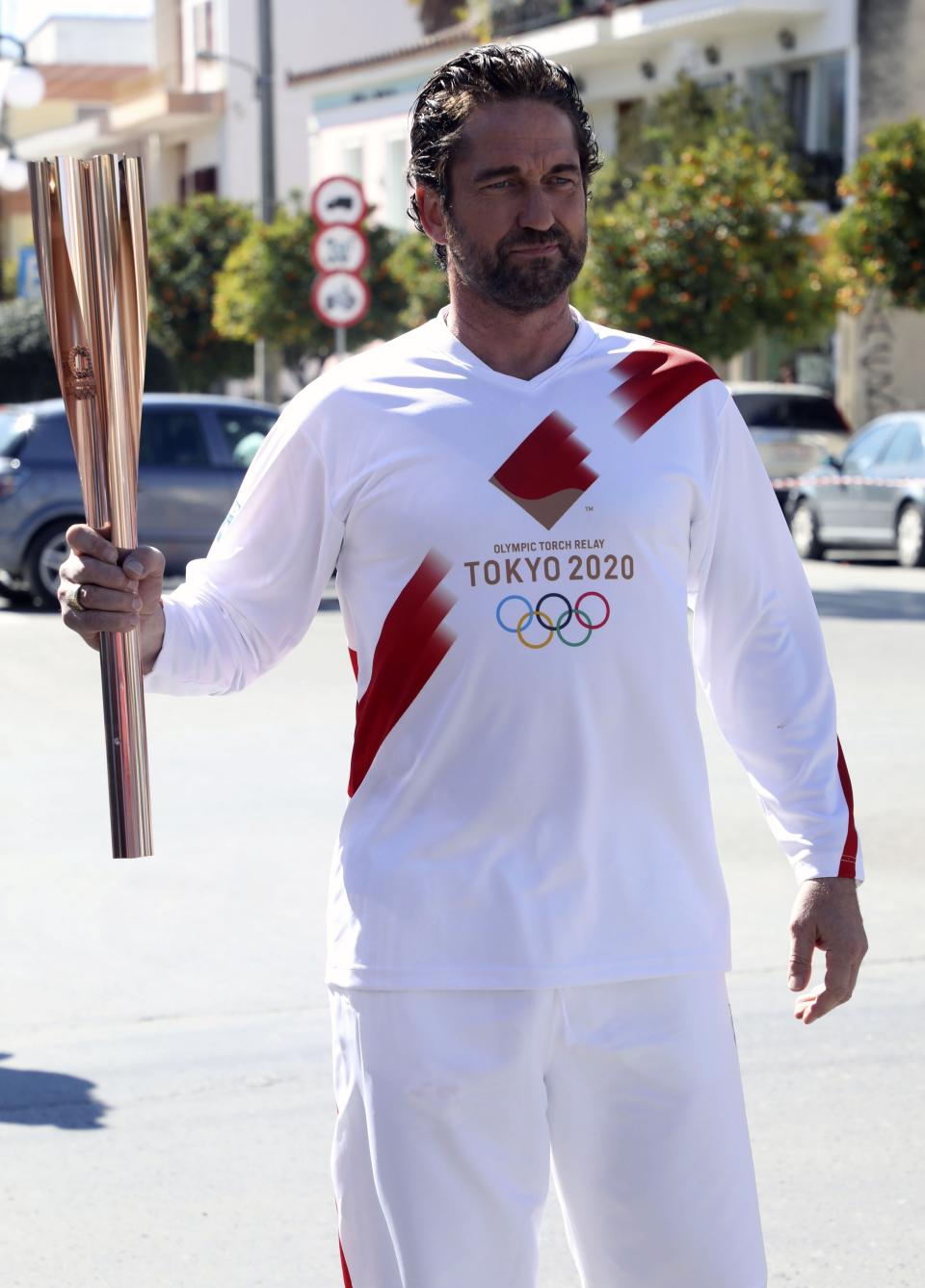 US actor Gerard Butler poses as a torchbearer during the Olympic torch relay of the 2020 Tokyo Olympic Games in the southern Greek town of Sparta, Friday, March 13, 2020. Greece's Olympic committee says it is suspending the rest of its torch relay for the Olympic flame due to the "unexpectedly large crowd" that gathered to watch despite repeated requests for the public to stay away to prevent the spread of the new coronavirus. (AP Photo)