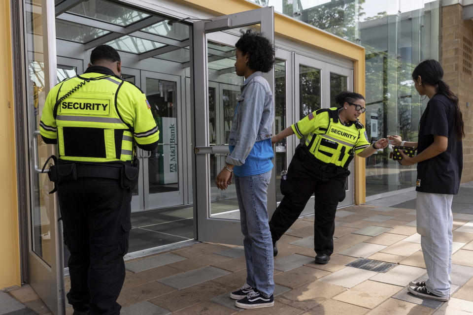 Security guards check identification for proof of age outside the Mall in Columbia, Friday, May 12, 2023, in Columbia, Md. The mall has implemented a "Parental Guidance Required" program, which requires that all visitors under 18 be accompanied by an adult who is at least 21-years-old after 4 p.m. on Fridays and Saturdays. (AP Photo/Julia Nikhinson)