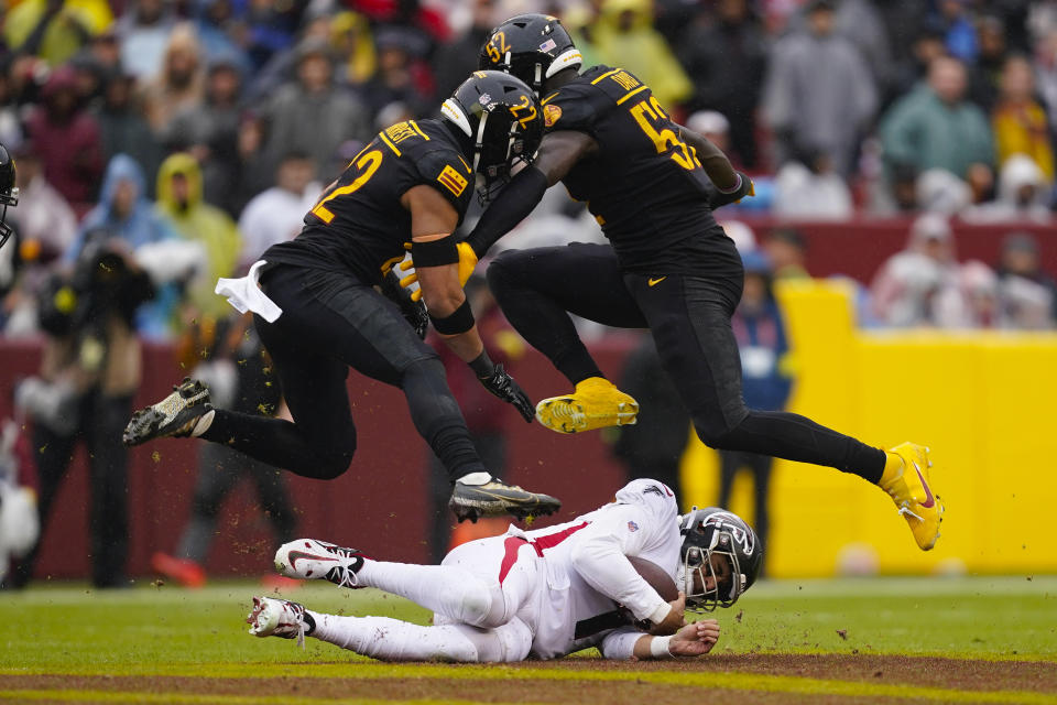 Atlanta Falcons quarterback Marcus Mariota (1) sliding to avoiding getting hit by Washington Commanders safety Darrick Forrest (22) and Washington Commanders linebacker Jamin Davis (52) during the first half of an NFL football game, Sunday, Nov. 27, 2022, in Landover, Md. (AP Photo/Patrick Semansky)