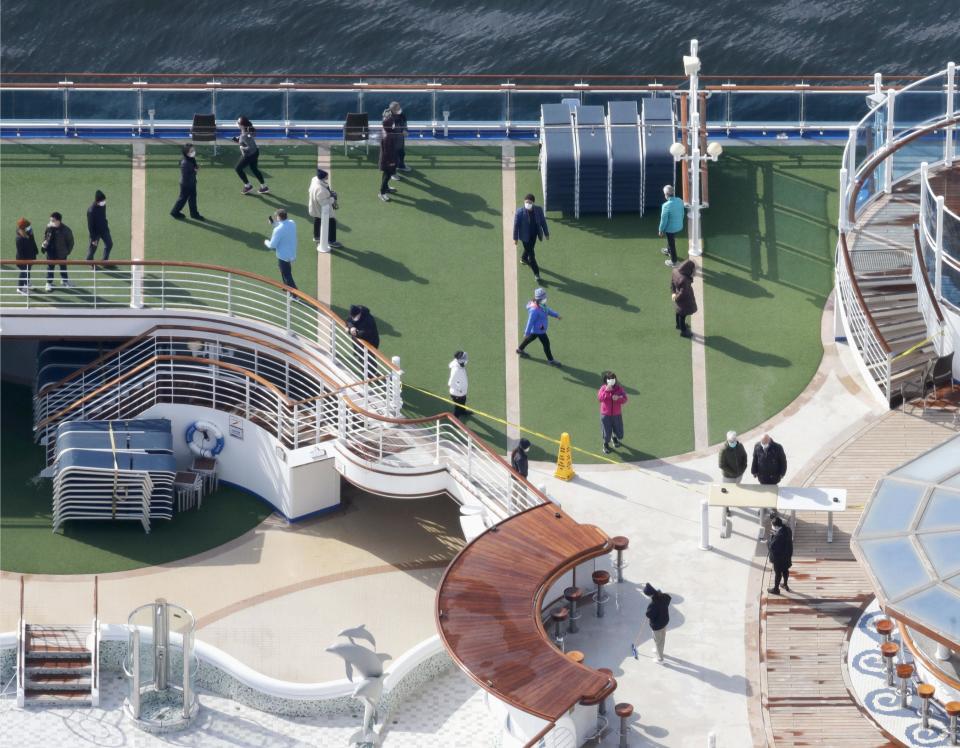 Photo taken from a Kyodo News helicopter show passengers strolling on the deck of the cruise ship Diamond Princess docked at the port of Yokohama.