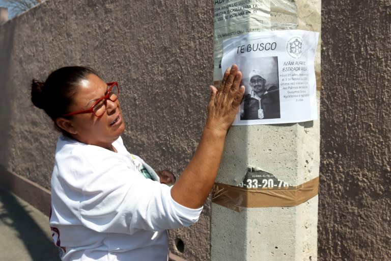 Azulema Estrada, pega un volante en un poste de luz con información sobre su hijo desaparecido, en Tlajomulco de Zúñiga, Jalisco, México (AFP/ULISES RUIZ)