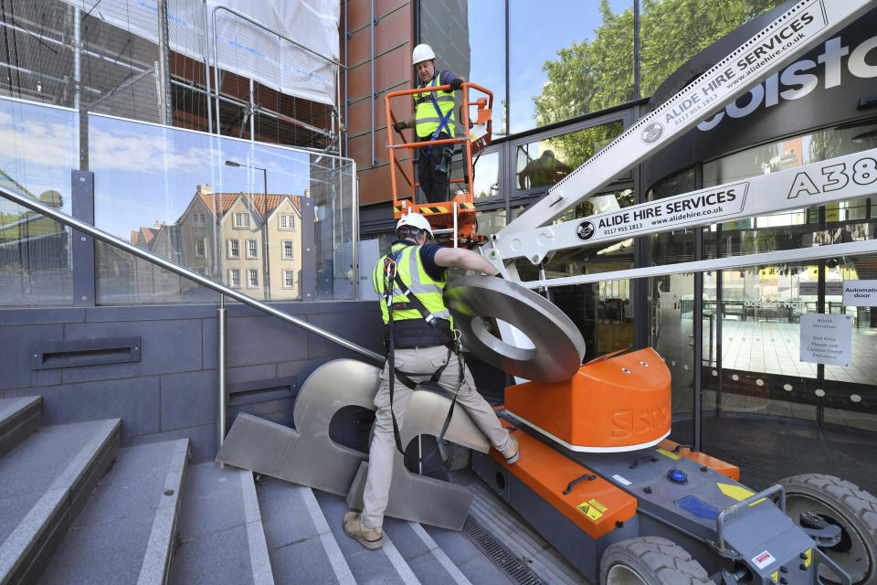 Contractors use an aerial platform outside Bristol music venue Colston Hall to remove the name of slave trader Edward Colston from its signage, in Bristol, England, Monday, June 15, 2020. The removal of the signage comes just over a week after a statue of Colston was hauled from its plinth by protesters in the English port city of Bristol and dumped in the Bristol harbour, during an anti-racism protest. (Ben Birchall/PA via AP)