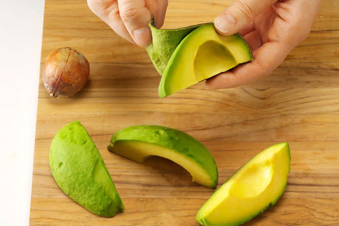 Peeling the skin from quartered avocado