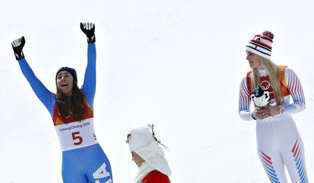 Alpine Skiing - Pyeongchang 2018 Winter Olympics - Women's Downhill - Jeongseon Alpine Centre - Pyeongchang, South Korea - February 21, 2018 - Bronze medallist Lindsey Vonn of the U.S. holding a Soohorang mascot plush doll looks on as gold medallist Sofia Goggia of Italy celebrates during the flower ceremony. REUTERS/Mike Segar