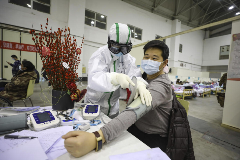 In this Feb. 18, 2020, photo, a medical staff member attends to a COVID-19 patient in a temporary hospital converted from an exhibition center in Wuhan in central China's Hubei province. The hospital, one of the dozen of its kind built in Wuhan, hosts COVID-19 patients with mild symptoms. (Chinatopix Via AP) CHINA OUT