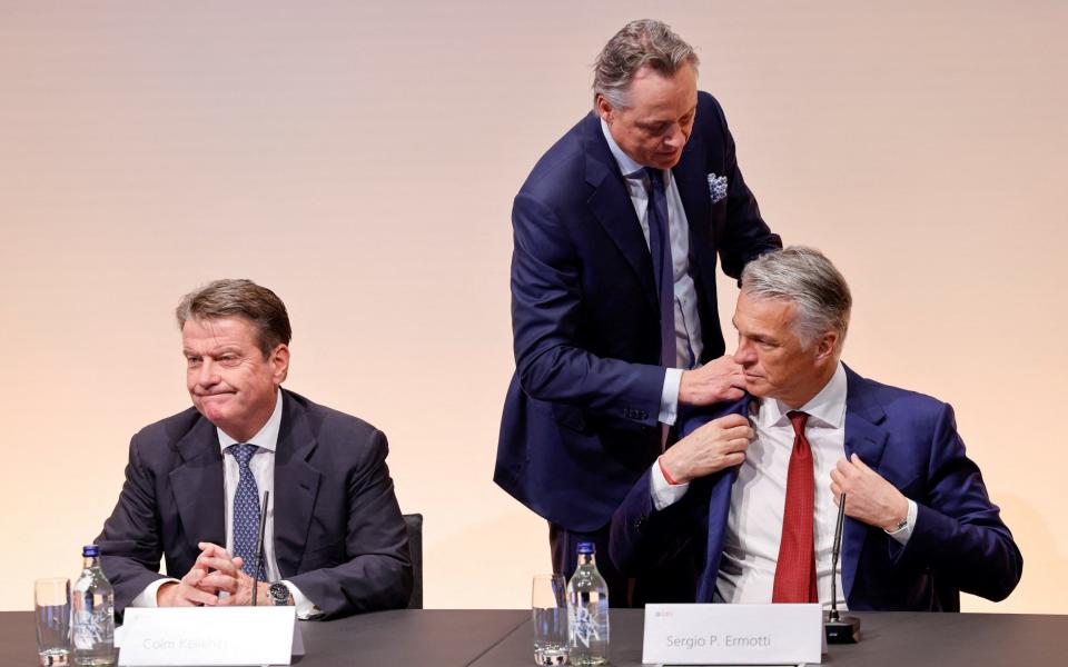 Former CEO and newly appointed advisor Ralph Hamers, adjusts the jacket of Sergio Ermotti, newly rehired CEO of UBS Group AG, while sitting next to UBS Chairman Colm Kelleher - REUTERS/Stefan Wermuth