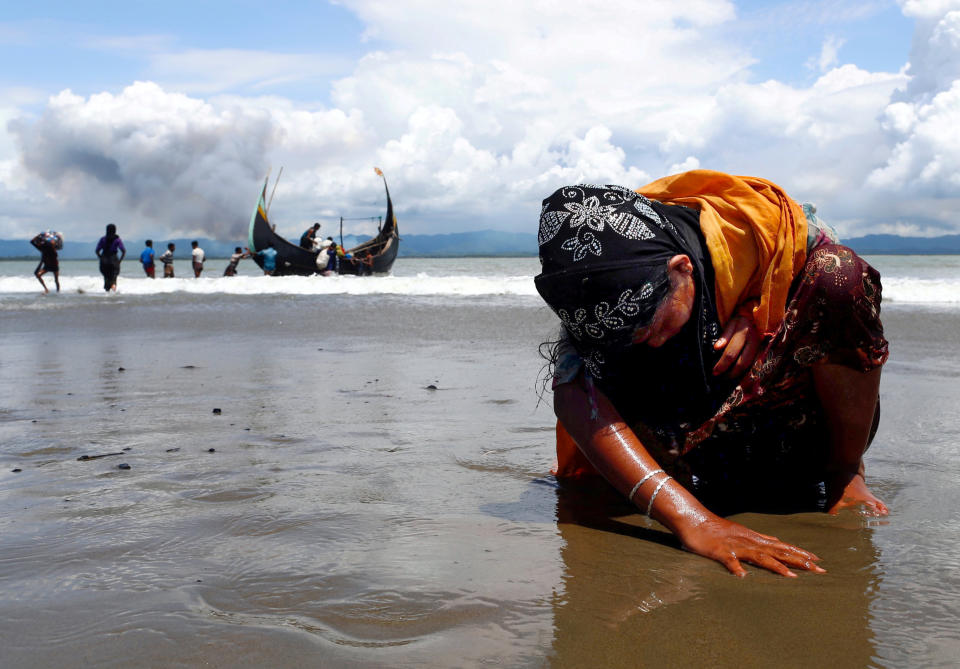 An exhausted Rohingya refugee woman touches the shore after crossing the Bangladesh-Myanmar border by boat through the Bay of Bengal, in Shah Porir Dwip, Bangladesd, on Sept. 11, 2017.