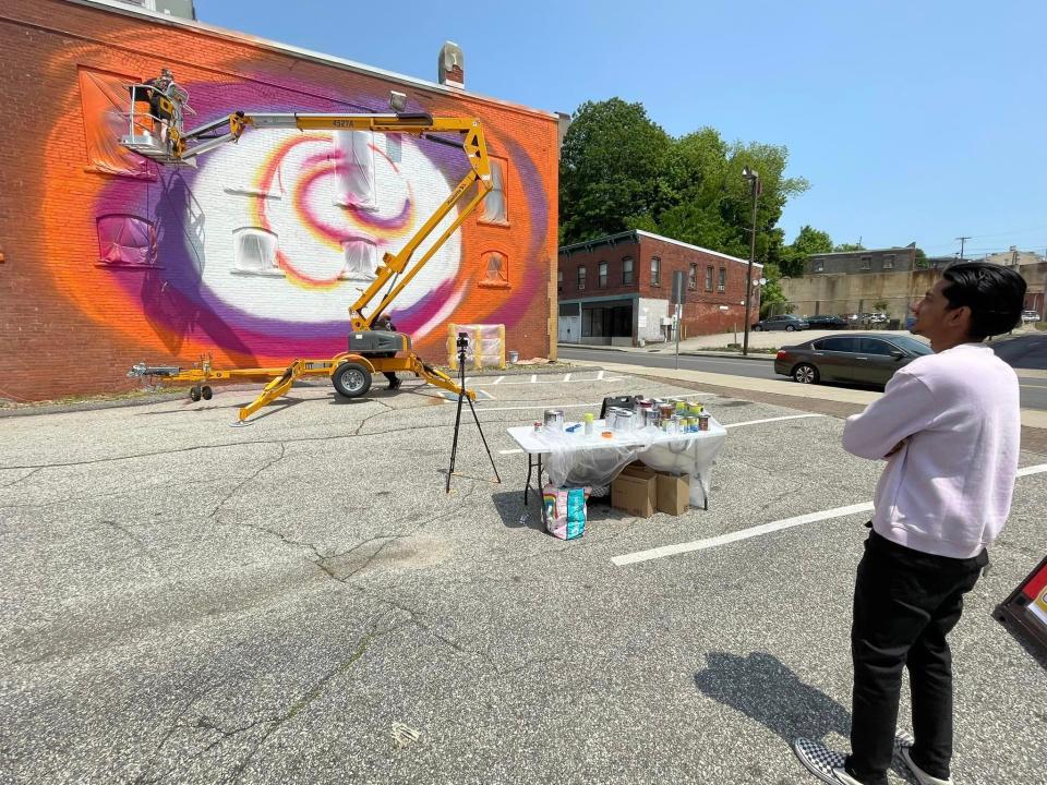 David Dessa, right, watches Faith Satterfield create her Breakthrough mural on Franklin Street.