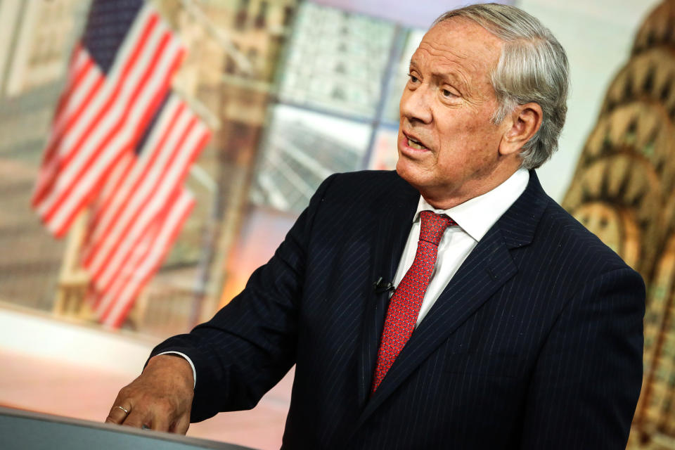 George Pataki, with three American flags and a picture of New York's Chrysler Building behind him.