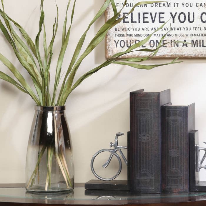 The round vase with a clear bottom and silver top on an entryway table 