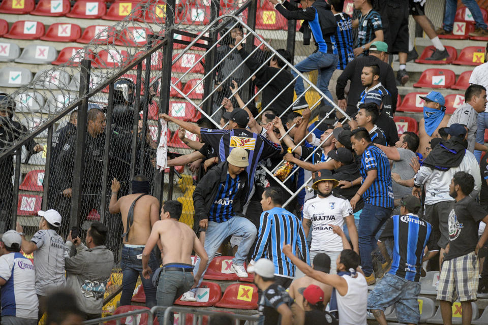 Fans clash during a Mexican soccer league match between the host Queretaro and Atlas from Guadalajara, at the Corregidora stadium, in Queretaro, Mexico, Saturday, March 5, 2022. Multiple people were injured during the brawl, including two critically. (AP Photo/Sergio Gonzalez)