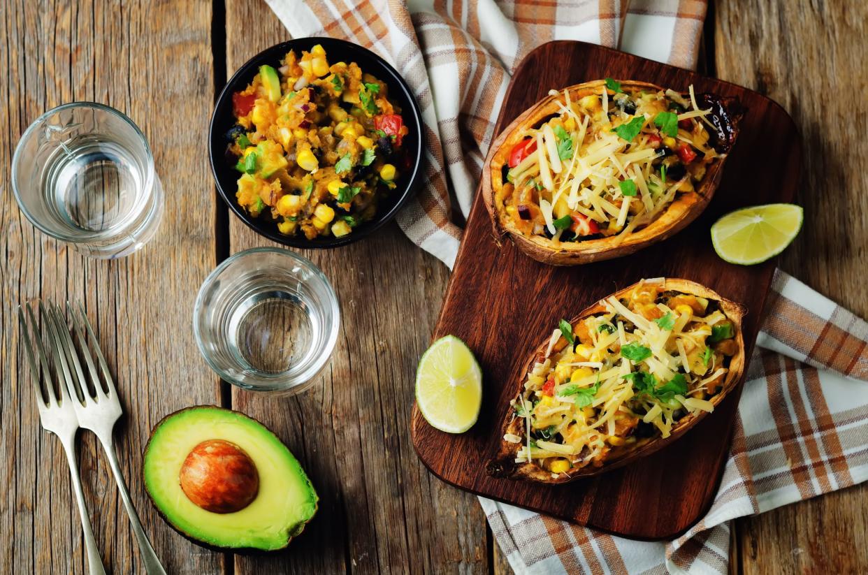 Black bean avocado corn stuffed sweet potatoes on a wood background. toning. selective focus