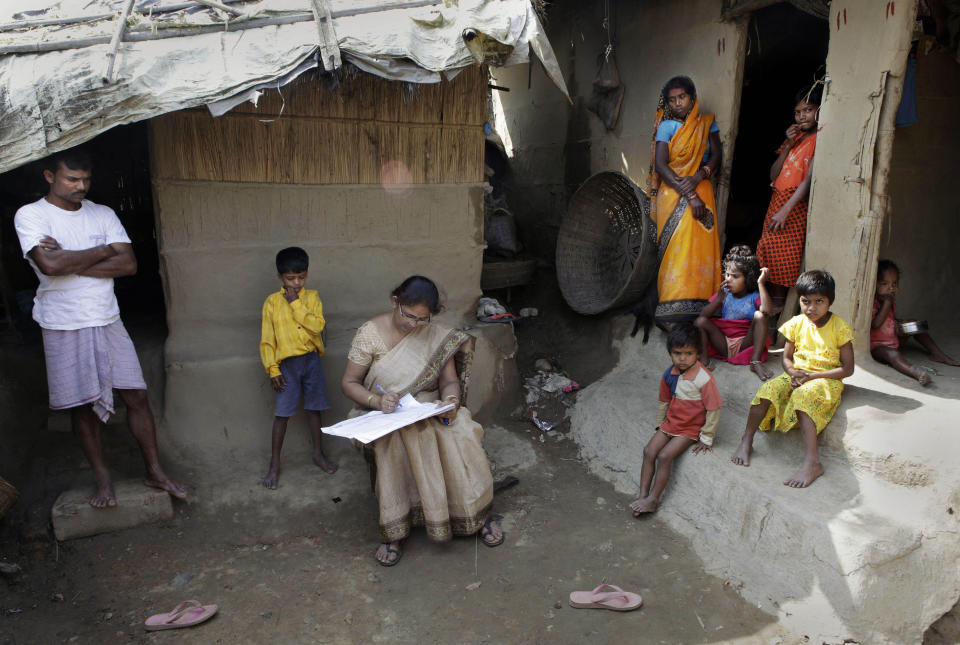 In this Thursday, April 1, 2010, file photo, Mahesh Shah, left, stands as his family members watch while a census worker Rumima Das, center, writes the information on a paper on the first day of the national census at Ramsingh Chapori village, east of Gauhati, India. India has been embroiled in protests since December, when Parliament passed a bill amending the country's citizenship law. (AP Photo/Anupam Nath, File)