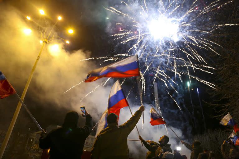 La gente ondea banderas nacionales rusas celebrando el reconocimiento de la independencia en el centro de Donetsk, el territorio controlado por los militantes prorrusos, en el este de Ucrania, a última hora del lunes 21 de febrero de 2022.