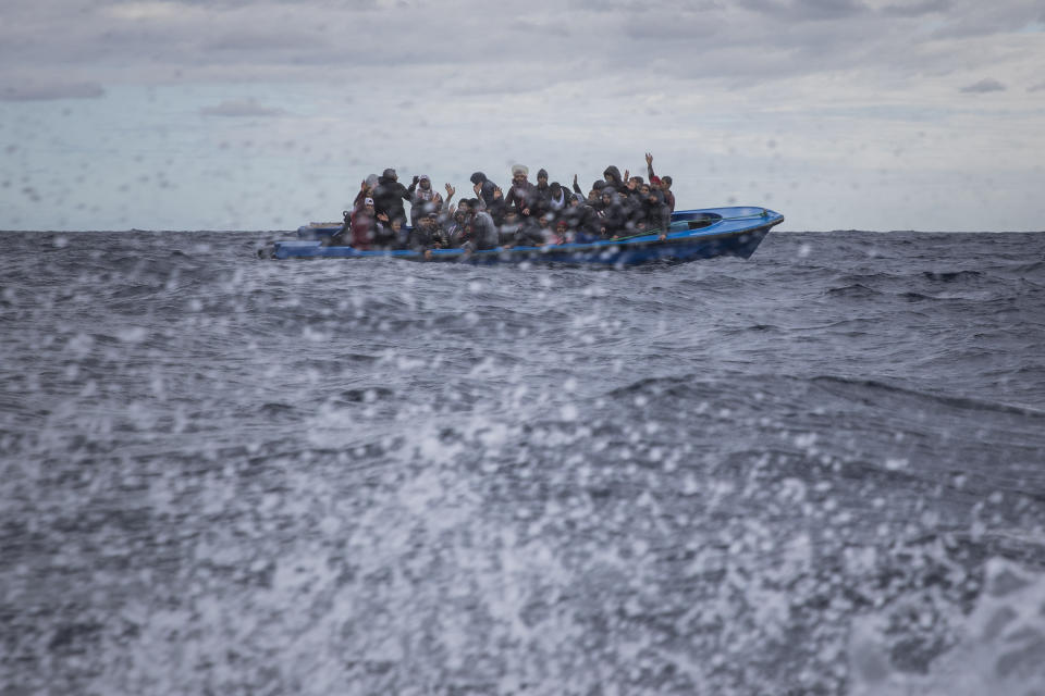 Men from Morocco and Bangladesh react on an overcrowded wooden boat, as aid workers of the Spanish NGO Open Arms approach them in the Mediterranean Sea, international waters, off the Libyan coast, Friday, Jan. 10, 2020. (AP Photo/Santi Palacios)