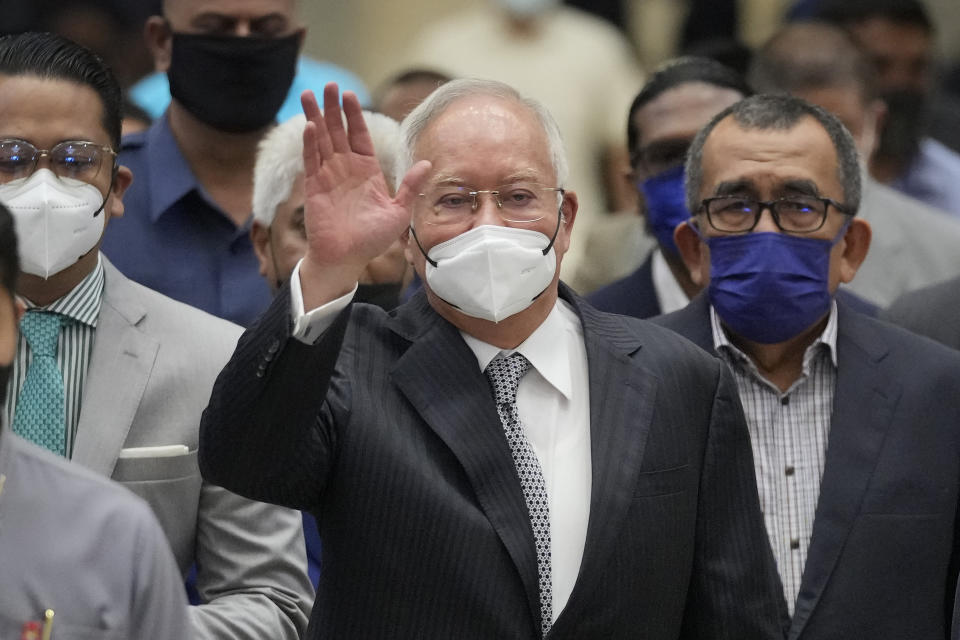 FILE - Former Malaysian Prime Minister Najib Razak, center, wearing a face mask, waves as he arrives at the Court of Appeal in Putrajaya, Malaysia, Tuesday, Aug. 23, 2022. Malaysia's Pardons Board said Friday, Feb. 2, 2024, it has reduced ex-Prime Minister Najib Razak's 12-year jail sentence by half and sharply cut the fine imposed after his corruption conviction. (AP Photo/Vincent Thian, File)