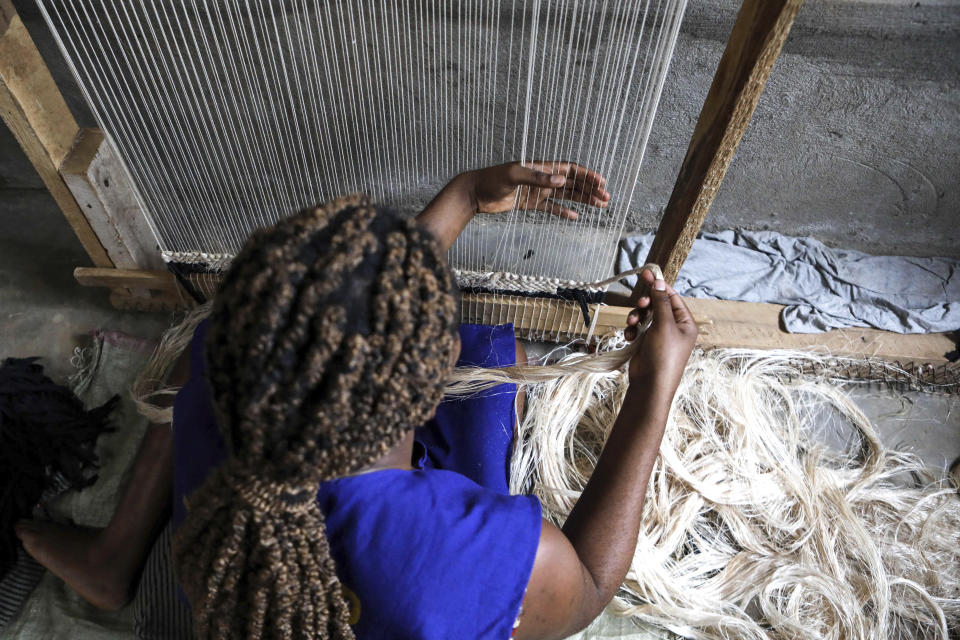 A worker weaves a carpet using banana fiber threads at Texfad factory in Sonde, Mukono District, Uganda, Wednesday, Sept. 20 2023. The decapitated banana plant is almost useless, an inconvenience to the farmer who must then uproot it and lay its dismembered parts as mulch. A Ugandan company is buying banana stems in a business that turns fiber into attractive handicrafts. The idea is innovative as well as sustainable in this East African country that’s literally a banana republic. (AP Photo/Hajarah Nalwadda)