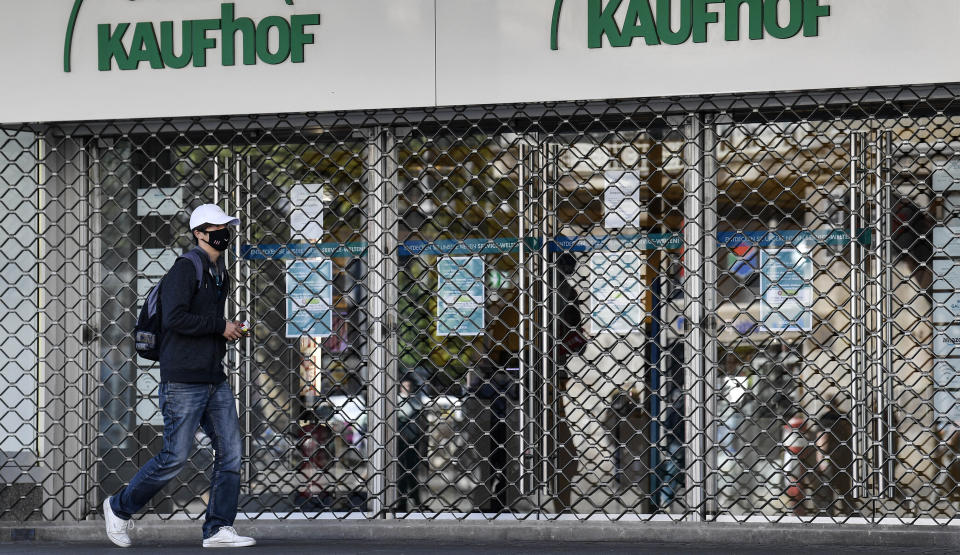 FILE - In this Monday, April 20, 2020 file photo, a man with a face mask to protect against the coronavirus walks past a Galeria Kaufhof warehouse as it is closed in Essen, Germany. German Federal Statistical Office released the preliminary figure for Germany’s gross domestic product and said the German economy shrank by 5 percent in the pandemic year 2020. (AP Photo/Martin Meissner, file)