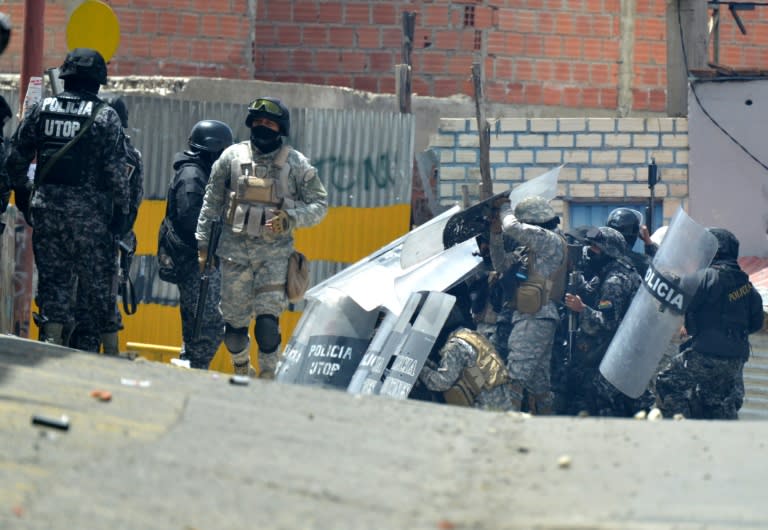 Anti-riot police agents shield themselves during clashes with Bolivian coca growers from Los Yungas region during a protest against a bill that caps legal coca crops extensions in La Paz on February 21, 2017