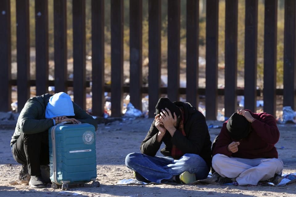 Migrants rest in the desert along the border wall as they join hundreds of migrants gathering along the border Tuesday, Dec. 5, 2023, in Lukeville, Ariz. (AP Photo/Ross D. Franklin)