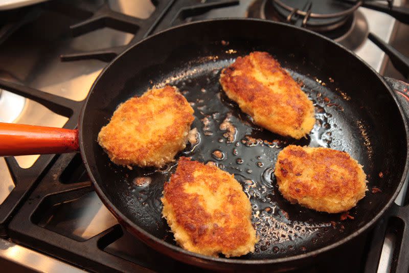 salmon patties frying in a cast iron pan