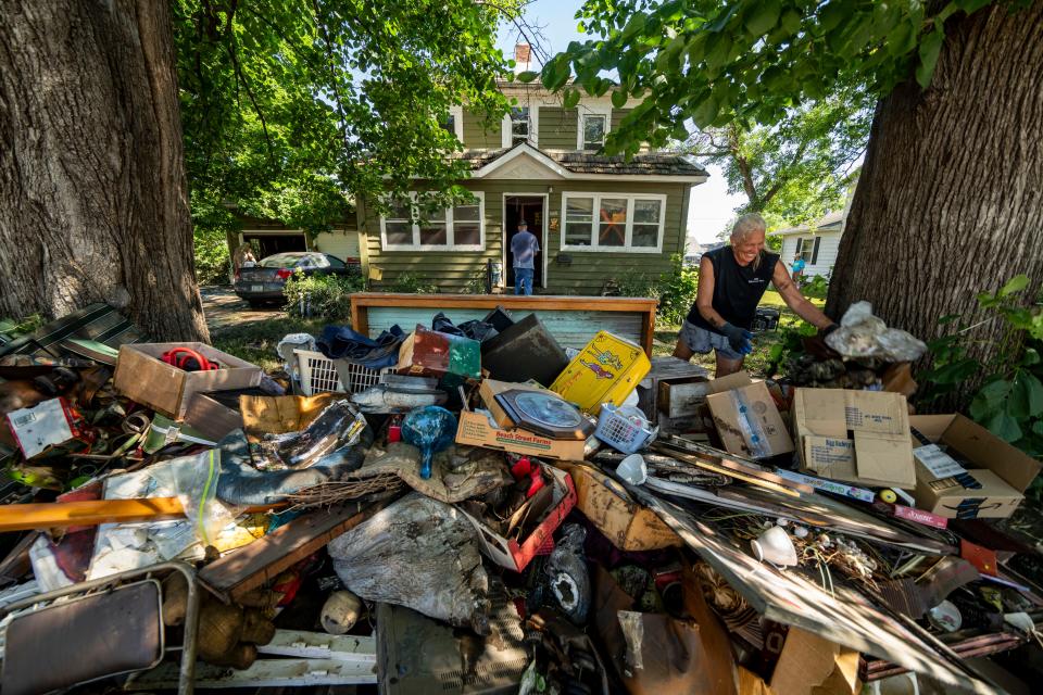 Kerri Hoogendoorn dumps waterlogged belongings on the lawn of a Rock Valley home Monday, June 24, 2024.