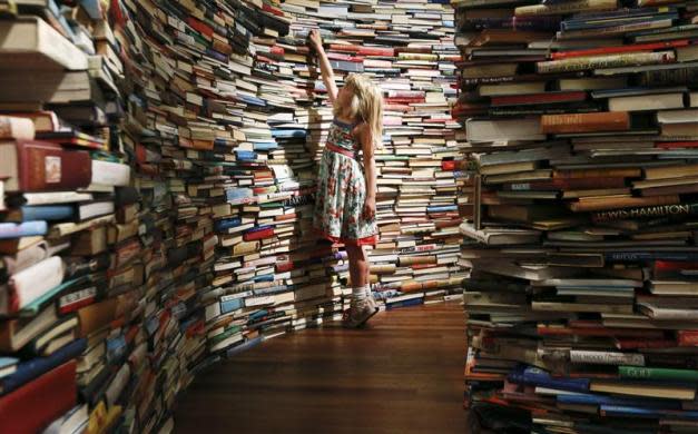 Leona, 7, poses inside a labyrinth installation made up of 250,000 books titled "aMAZEme" by Marcos Saboya and Gualter Pupo at the Royal Festival Hall in central London July 31, 2012.