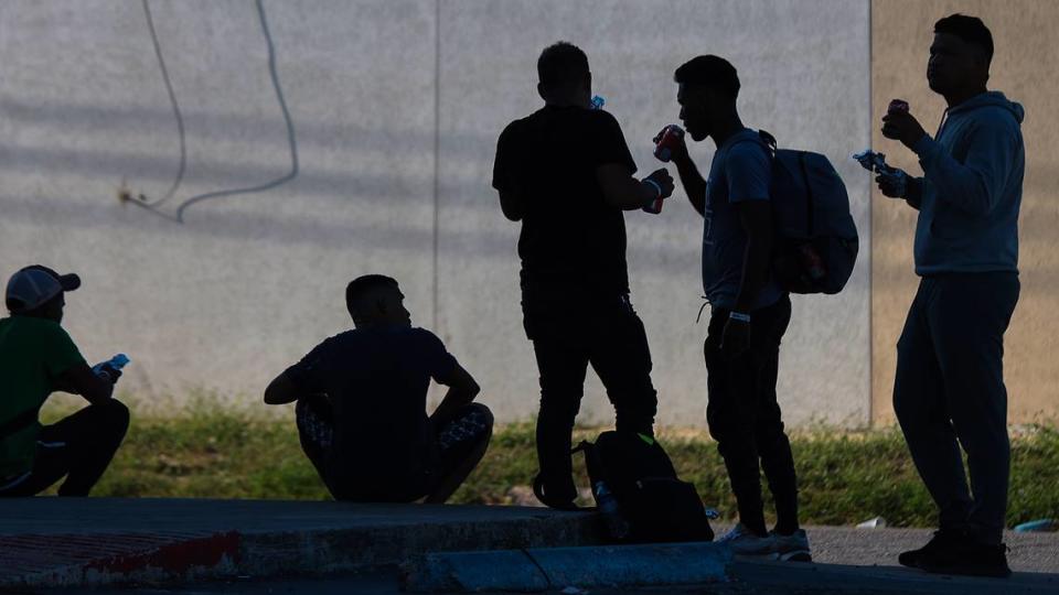 A group of Venezuelan migrant men enjoy a donated food and beverages as they sit in the shade to escape the hot Texas sun. On Wednesday, Sept. 21, 2022 a group of locals handed out food and beverages to migrants across the street from the Migrant Resource Center, where many are housed for period of three days in San Antonio, Texas.