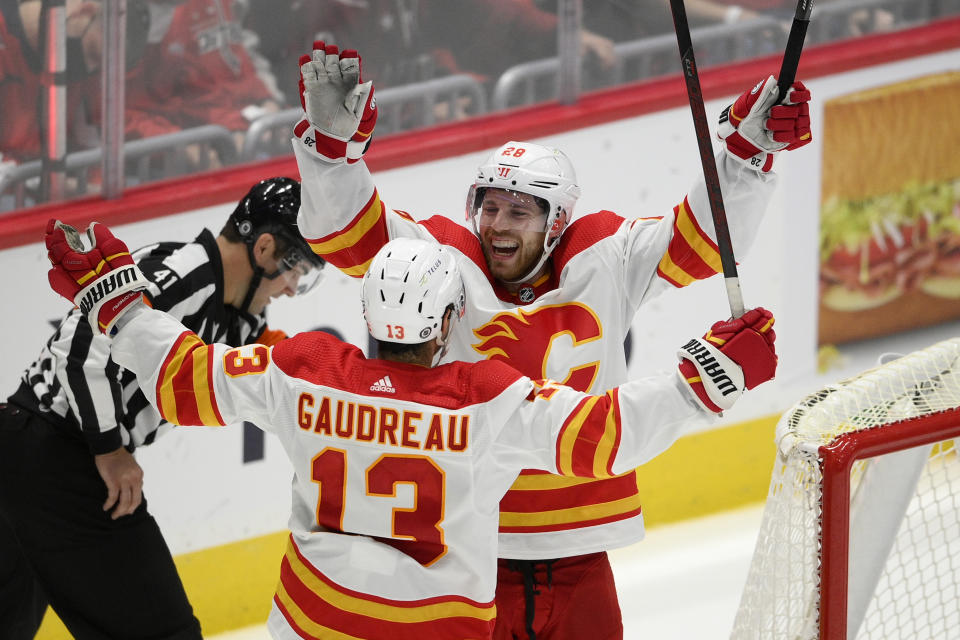 Calgary Flames center Elias Lindholm (28) celebrates with left wing Johnny Gaudreau (13) after scoring the game-winning goal in overtime of an NHL hockey game against the Washington Capitals, Saturday, Oct. 23, 2021, in Washington. The Flames won 4-3 in overtime. (AP Photo/Nick Wass)