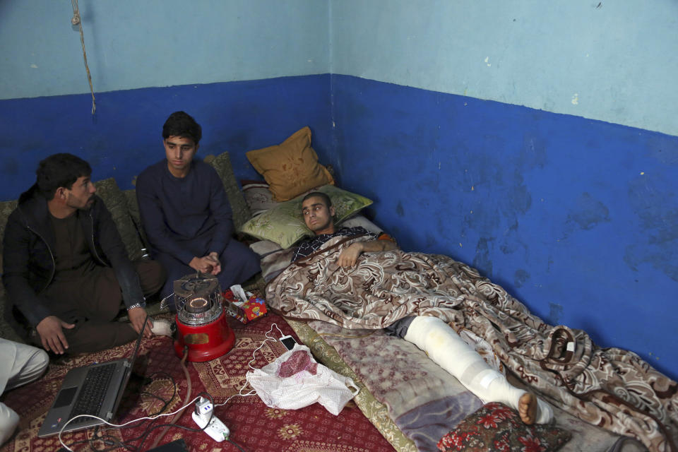 Nawid, a 21-year-old student who lost his brother and who was himself wounded in a deadly Taliban suicide attack on the Afghan capital's Green Village neighborhood earlier this month, receives visitor as he lies in bed at home in Kabul, Afghanistan, Tuesday, Jan. 29, 2019. Kabul residents are wary of peace talks with the Taliban, even as Afghan officials express hope that negotiations could lead to lasting peace in their war-ravaged country. (AP Photo/Rahmat Gul)