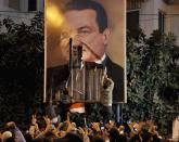 FILE - In this Jan. 25, 2011 file photo, demonstrators deface a poster of Egyptian President Hosni Mubarak in Alexandria, Egypt. The 2011 uprising led to the quick ouster of autocrat Mubarak. A decade later, thousands are estimated to have fled abroad to escape a state, headed by President Abdel Fattah el-Sissi, that is even more oppressive. (AP Photo, File)