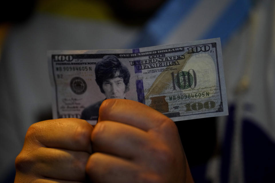 A supporter of presidential candidate of the Liberty Advances coalition Javier Milei holds a fake 100 dollar bill with Milei´s face during a campaign rally in Buenos Aires, Argentina, Wednesday, Oct. 18, 2023. General elections are set for Oct. 22. (AP Photo/Natacha Pisarenko)