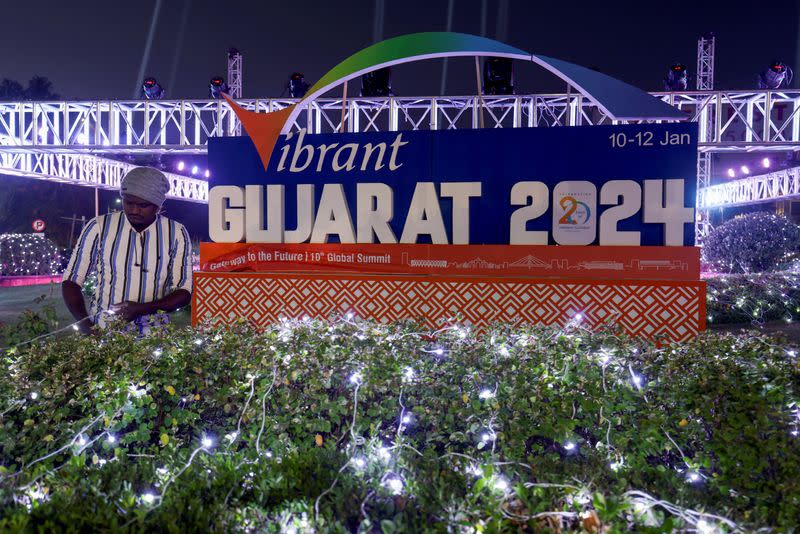 An electrician sets up lamps on a plant in front of Vibrant Gujarat Global Summit, in Ahmedabad