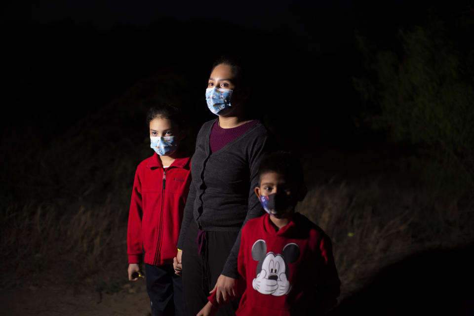 FILE - In this March 24, 2021, file photo, Fatima Nayeli, 13, center, talks to journalists as she holds the hand of her sister, Cynthia Stacy, 8, and Davidson Jair, 7, after they were smuggled on an inflatable raft across the Rio Grande river in Roma, Texas. All three children traveled from El Salvador in the hope of reaching relatives living in the U.S. Confronted with a stream of unaccompanied children crossing the border from Mexico, the U.S. government has awarded shelter-construction and management contracts to private companies that critics say may not be equipped to adequately care for the minors. (AP Photo/Dario Lopez-Mills, File)