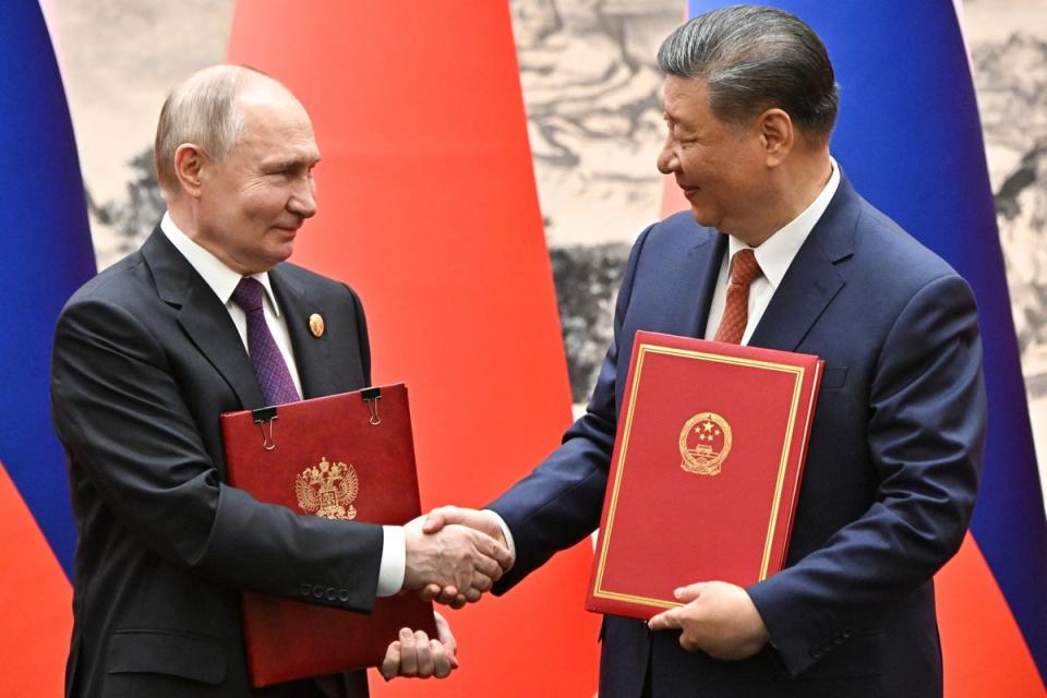 Russian President Vladimir Putin (L) and Chinese President Xi Jinping shake hands as they attend a signing ceremony following a meeting in expanded format at the Great Hall of the People (EPA)
