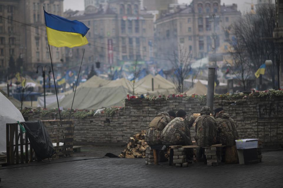 Anti-Yanukovych protesters warm themselves next to a fire in Kiev's Independence Square, Ukraine, Wednesday, March 5, 2014. Stepping back from the brink of war, Vladimir Putin talked tough but cooled tensions in the Ukraine crisis Tuesday, saying Russia has no intention "to fight the Ukrainian people" but reserves the right to use force. As the Russian president held court in his personal residence, U.S. Secretary of State John Kerry met with Kiev's fledgling government and urged Putin to stand down. (AP Photo/Emilio Morenatti)