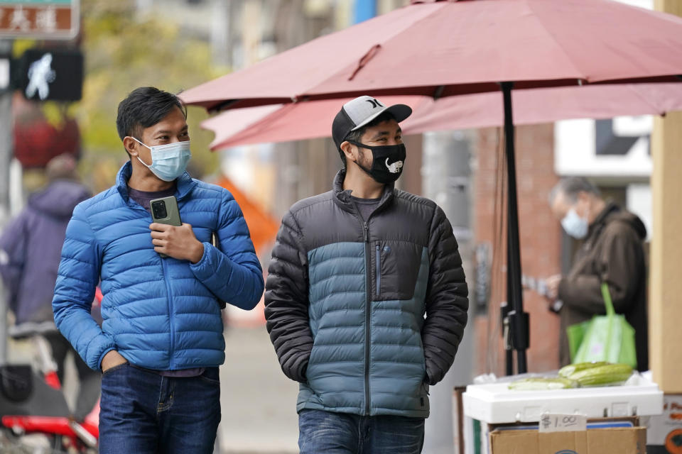 Pedestrians wearing masks walk past a small grocery store in the Chinatown-International District Thursday, Nov. 12, 2020, in Seattle. Washington state and county health officials have warned of a spike in coronavirus cases across the state, and pleaded with the public to take the pandemic more seriously heading into the winter holidays. (AP Photo/Elaine Thompson)