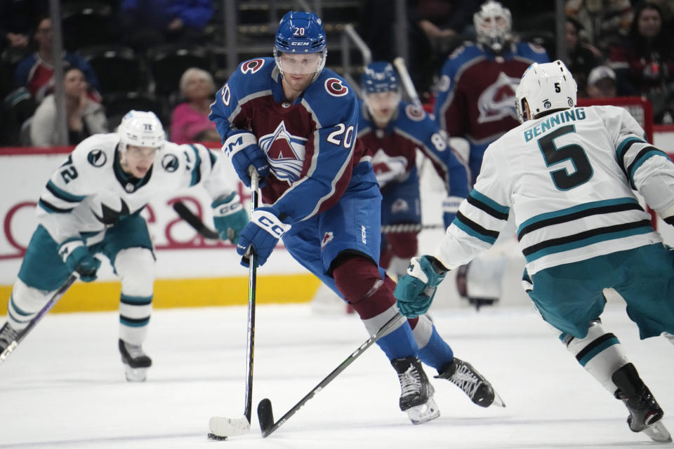 Colorado Avalanche center Lars Eller, middle, collects the puck between San Jose Sharks defenseman Matt Benning, front, and left wing William Eklund in the third period of an NHL hockey game Tuesday, March 7, 2023, in Denver. (AP Photo/David Zalubowski)