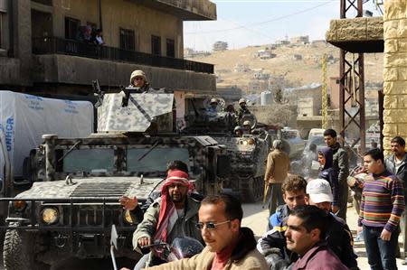 Residents watch Lebanese army soldiers on their military vehicles entering the Sunni Muslim border town of Arsal, in eastern Bekaa Valley March 19, 2014. REUTERS/Hassan Abdallah