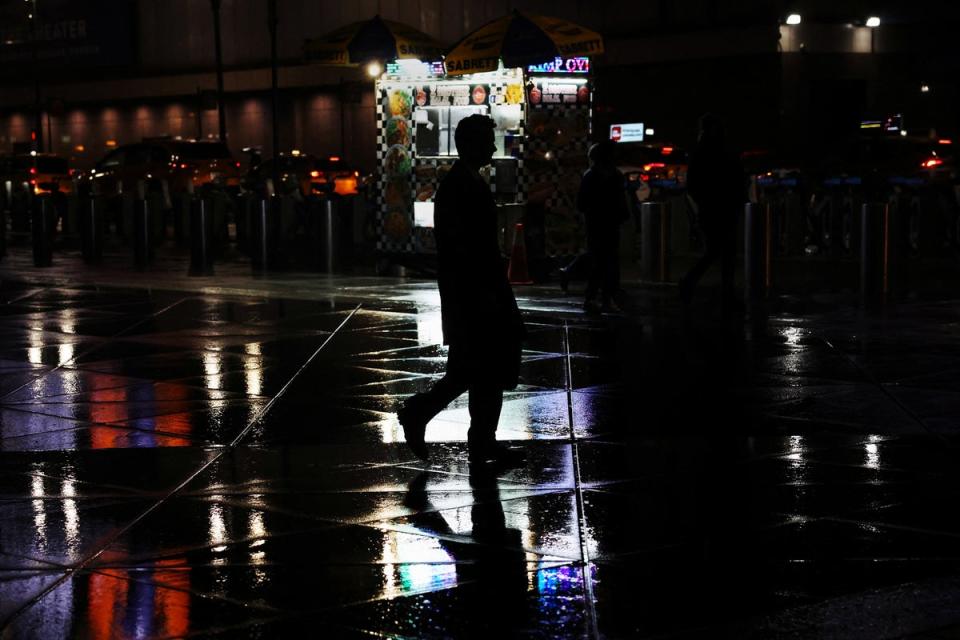 A man walks through heavy rain near Pennsylvania Station in New York City on April 2, 2024 (REUTERS)