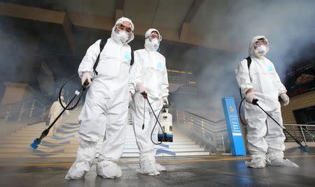 Workers in full protective gear disinfect the floor of a subway station in Seoul, South Korea, June 11, 2015. REUTERS/Kim Do-hoon/Yonhap