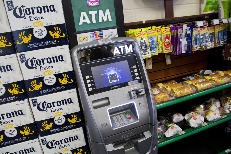 FILE - In this April 18, 2018, file photo, an ATM machine is in use at a New York convenience store. If you find yourself short on cash while on vacation, it might seem easiest to hit up the nearest ATM. But if that handy machine is not in your bank’s network, you could get a double whammy of fees: The ATM owner will probably charge a few dollars for the convenience, and your own bank may tack on an extra $2.50 or so. (AP Photo/Mark Lennihan, File)