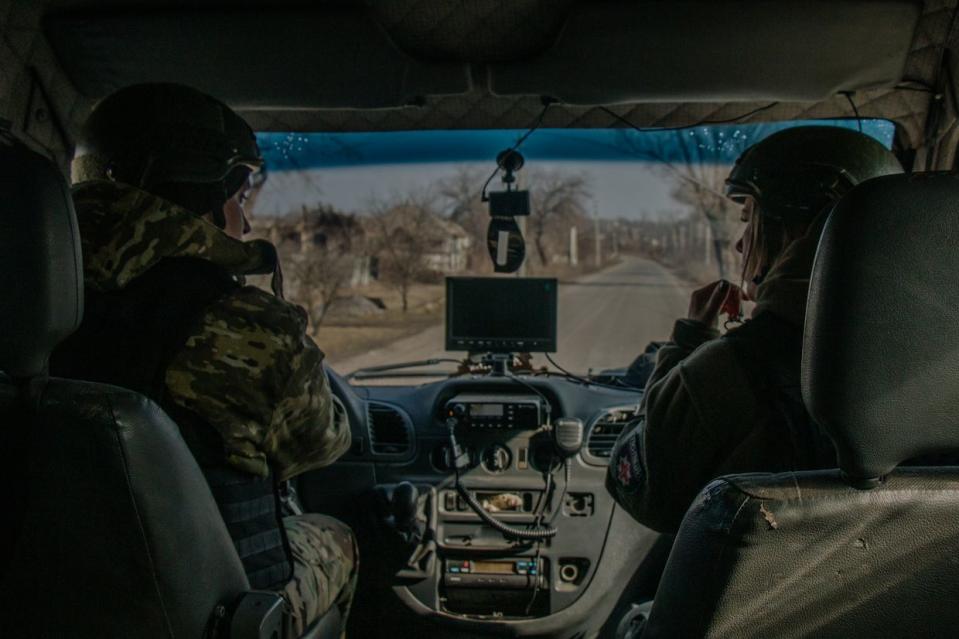 <em>Editor’s note: part of the image was blurred out for safety reasons. </em>Valeriia Chernikova (R) and Dmytro Bilenets (L), the White Angel crew members, ride the white armored bus outside Lyman in Donetsk Oblast on March 7, 2024. (Alexander Khrebet / The Kyiv Independent)