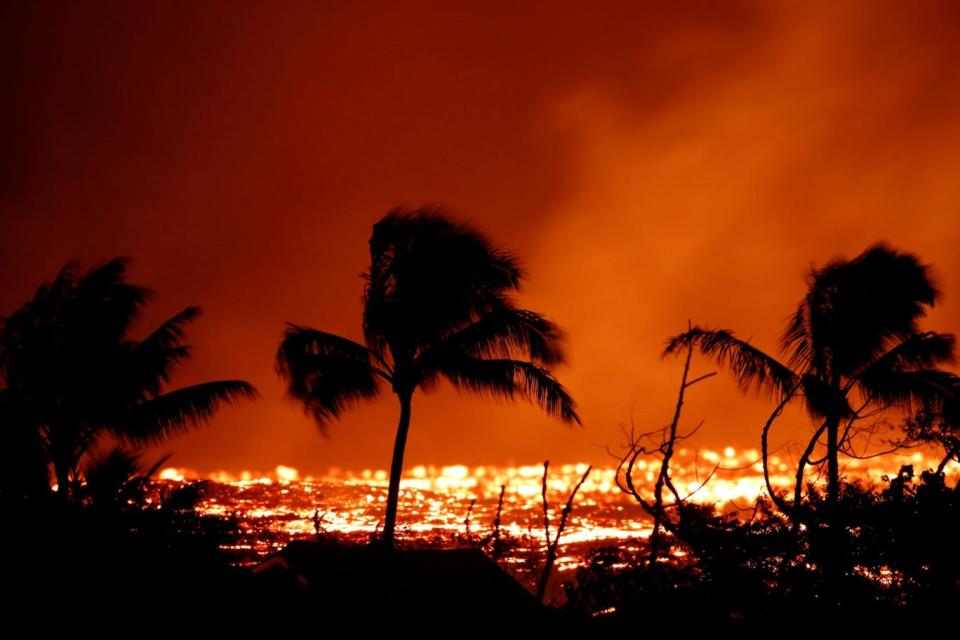 Lava flows past trees on the outskirts of Pahoa during ongoing eruptions of the Kilauea Volcano in Hawaii (REUTERS)
