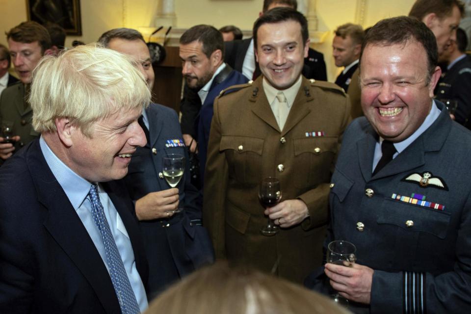 Prime Minister Boris Johnson, left, speaks to guests at the military reception (AP)